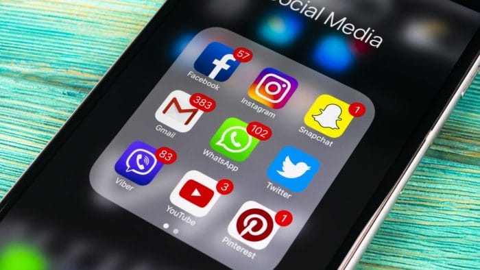 Smartphone with icons of social media on screen on wooden table. Smartphone life style smartphone. Starting social media app. Office shot